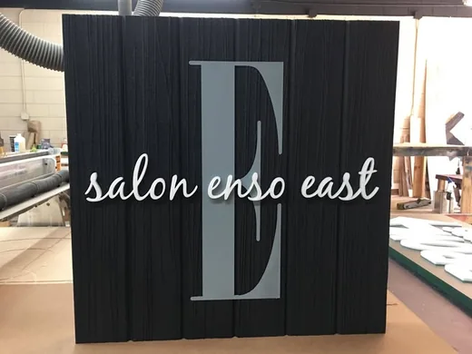 Salon Enso East black textured sign with raised script lettering and dimensional monogram